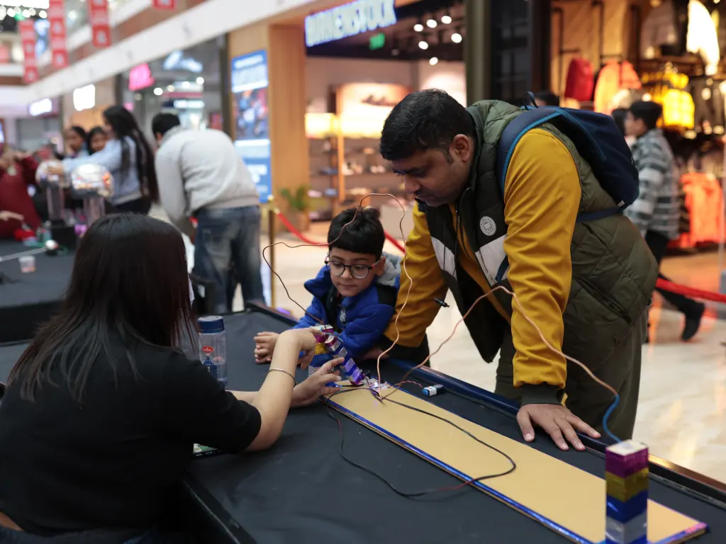 A father and young son wiring an electronics circuit at a MakerMasti mall activation
