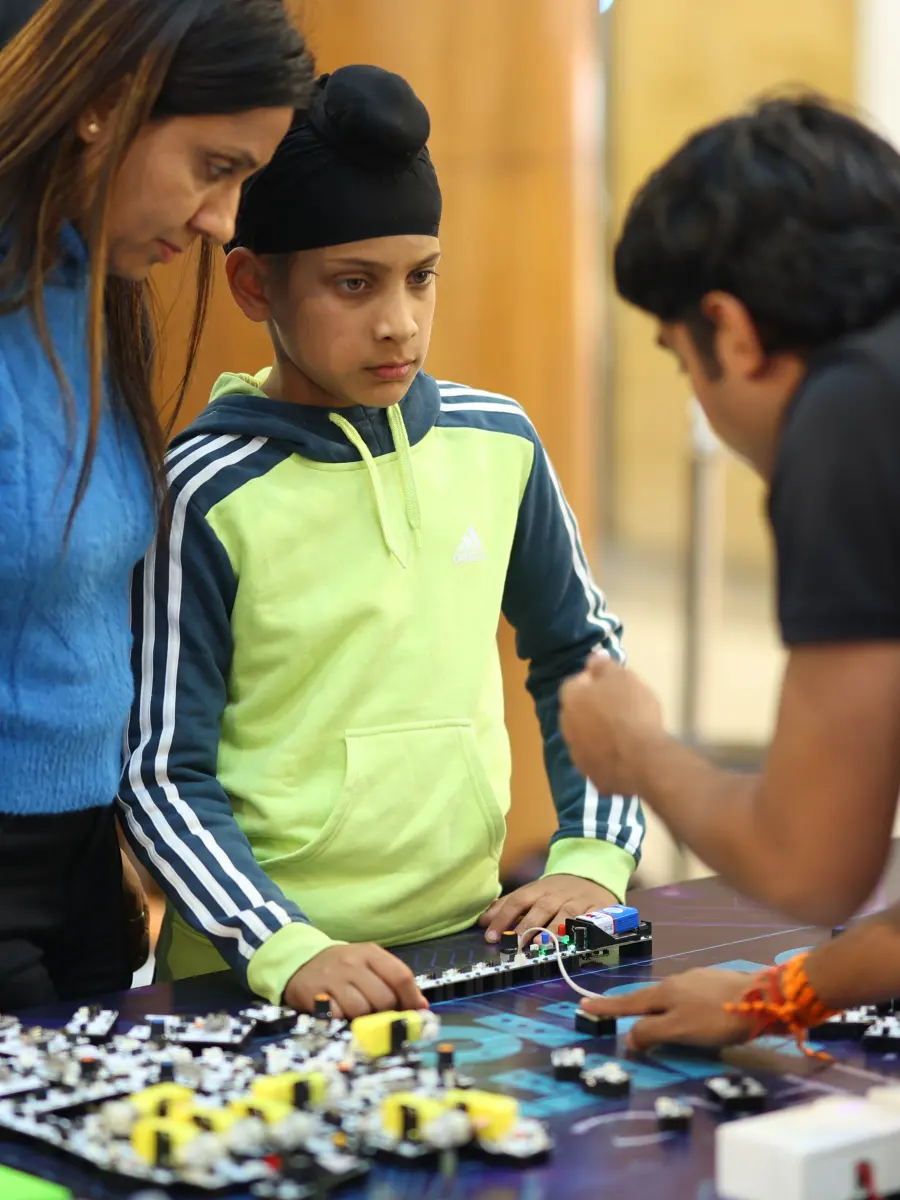 A boy building a motorised robotics project with help from a MakerMasti host