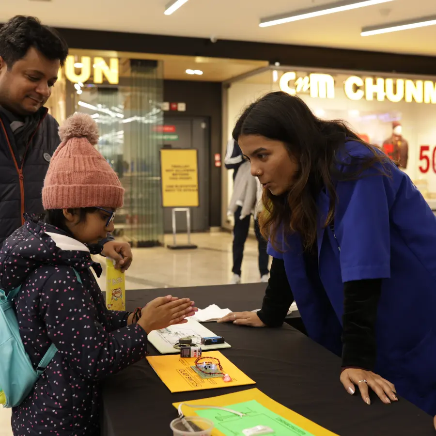A child trying a smart-sensor experiment with MakerMasti hosts at a mall stand