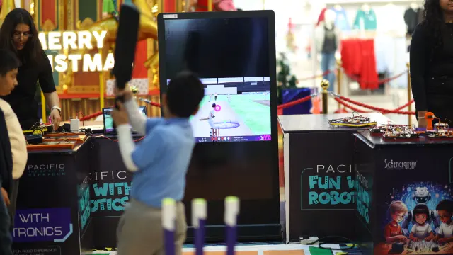 A boy playing a motion-controlled cricket game at a co-branded MakerMasti brand activation stand