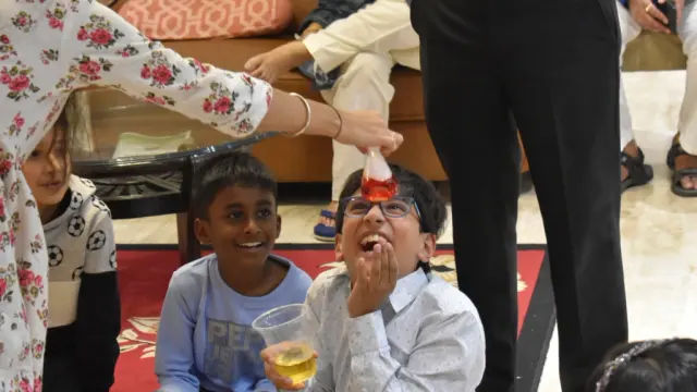 Two boys laughing as a MakerMasti host pours a colour-changing potion at a science birthday party