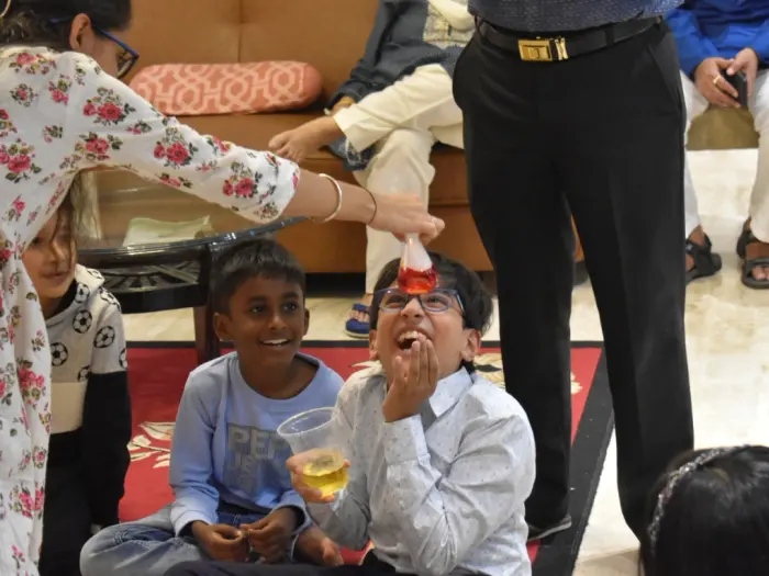 Two boys laughing as a MakerMasti host pours a colour-changing potion at a science birthday party